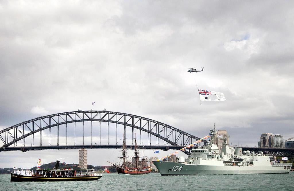 A Royal Australian Navy S-70B Sea Hawk helicopter flies the Australian White Ensign over HMAS Parramatta, HM Bark Endeavour and  Lady Hopetoun in Sydney Harbour for the International Fleet Review launch. <br />
 © SW
